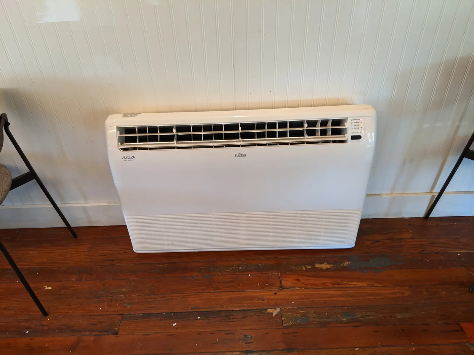 Fujitsu floor-mounted mini split against a beadboard wall on an old wood floor