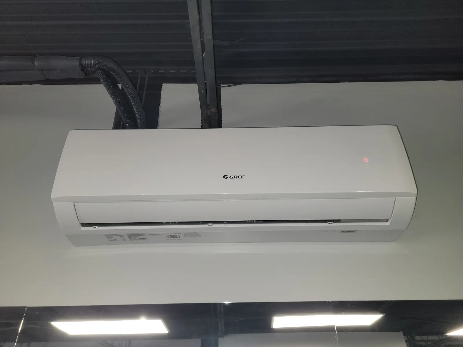 Gree wall-mounted mini split under an exposed black ceiling in a commercial space