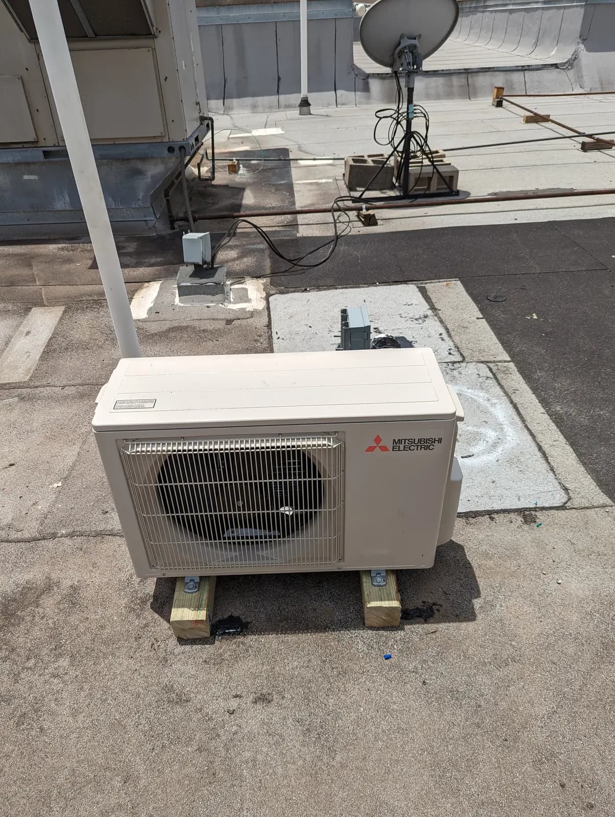 Mitsubishi Electric outdoor unit on wood sleepers on a flat commercial roof