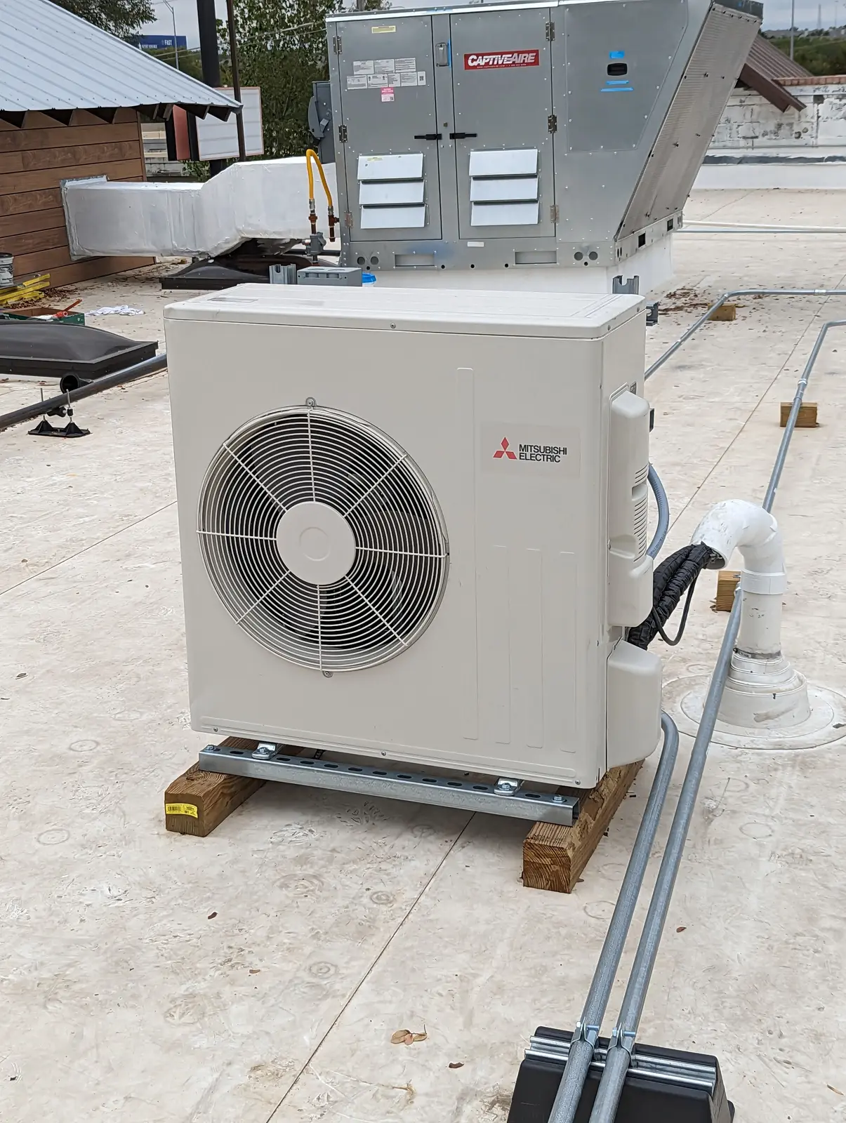 Mitsubishi Electric outdoor unit on a commercial roof next to a rooftop HVAC unit