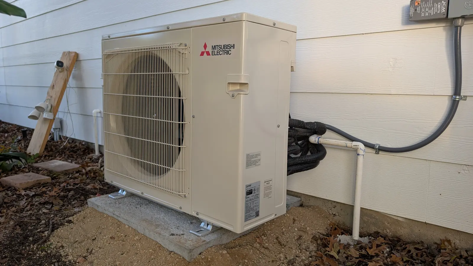 Mitsubishi Electric outdoor unit with lines and conduit along white siding