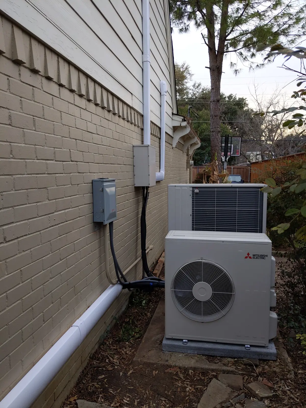Mitsubishi outdoor unit with line hide cover running along a brick wall in a side yard