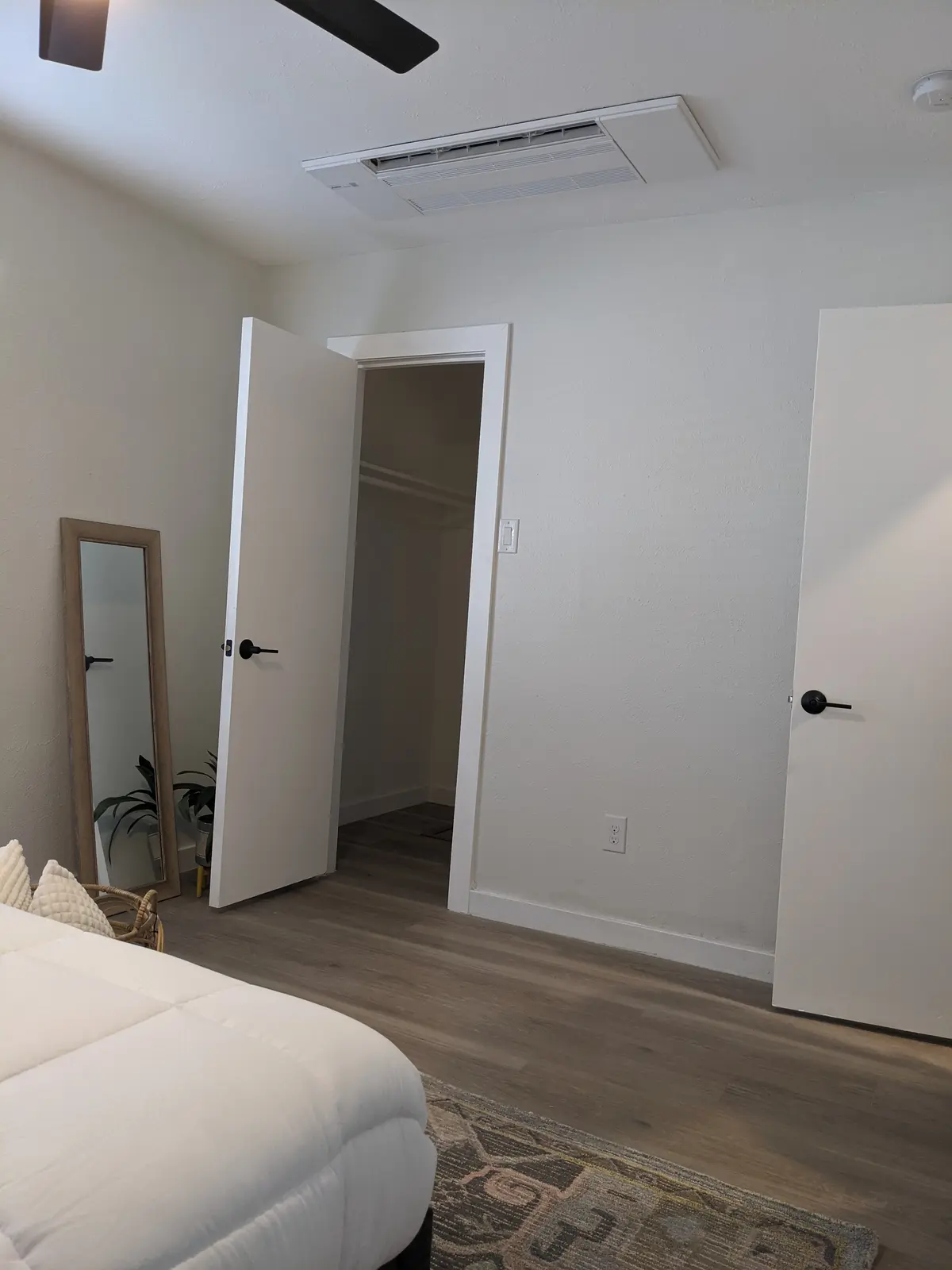 Bedroom with a one-way ceiling cassette mini split above an open door and closet