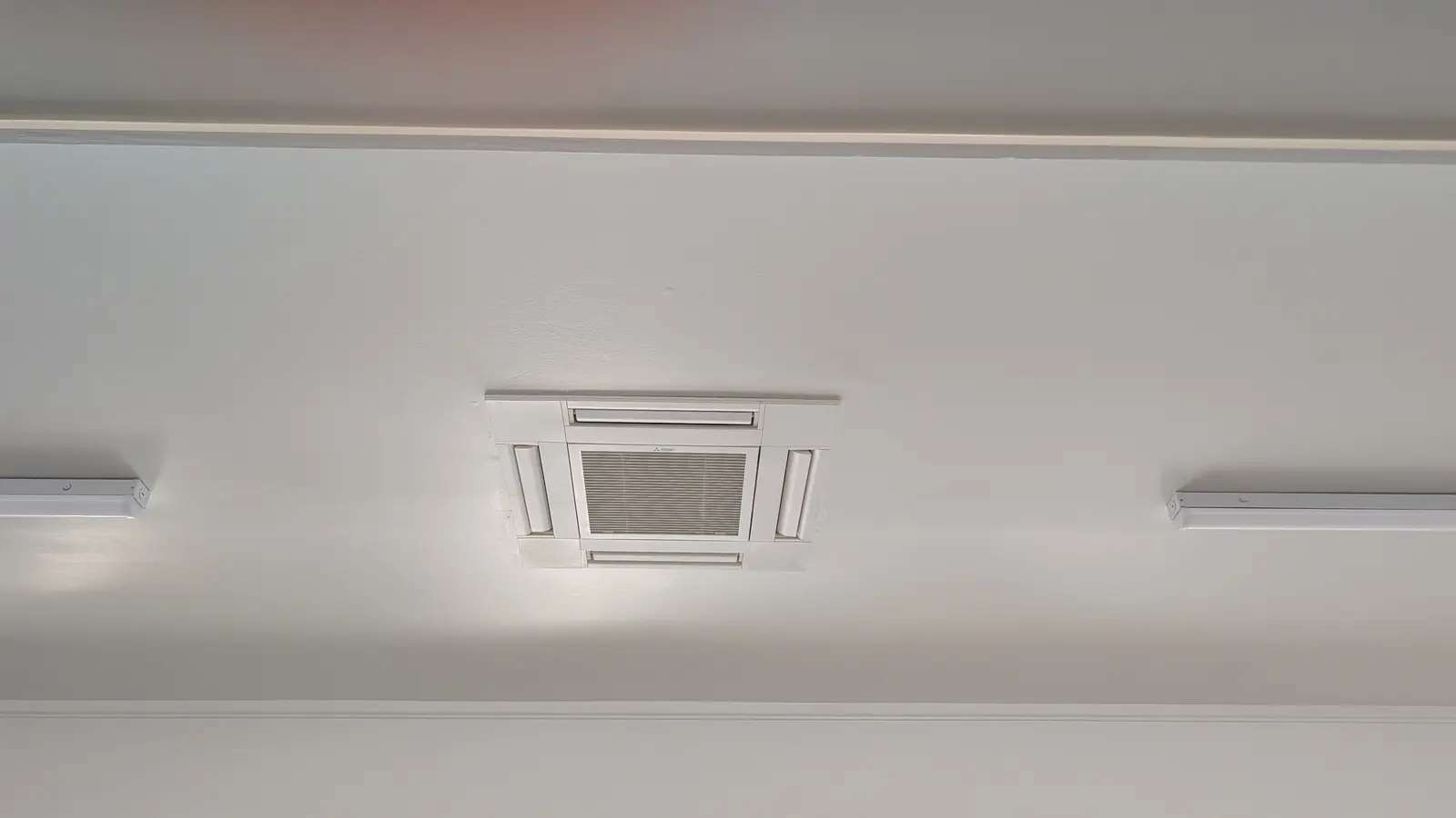 Compact four-way ceiling cassette between ceiling light fixtures
