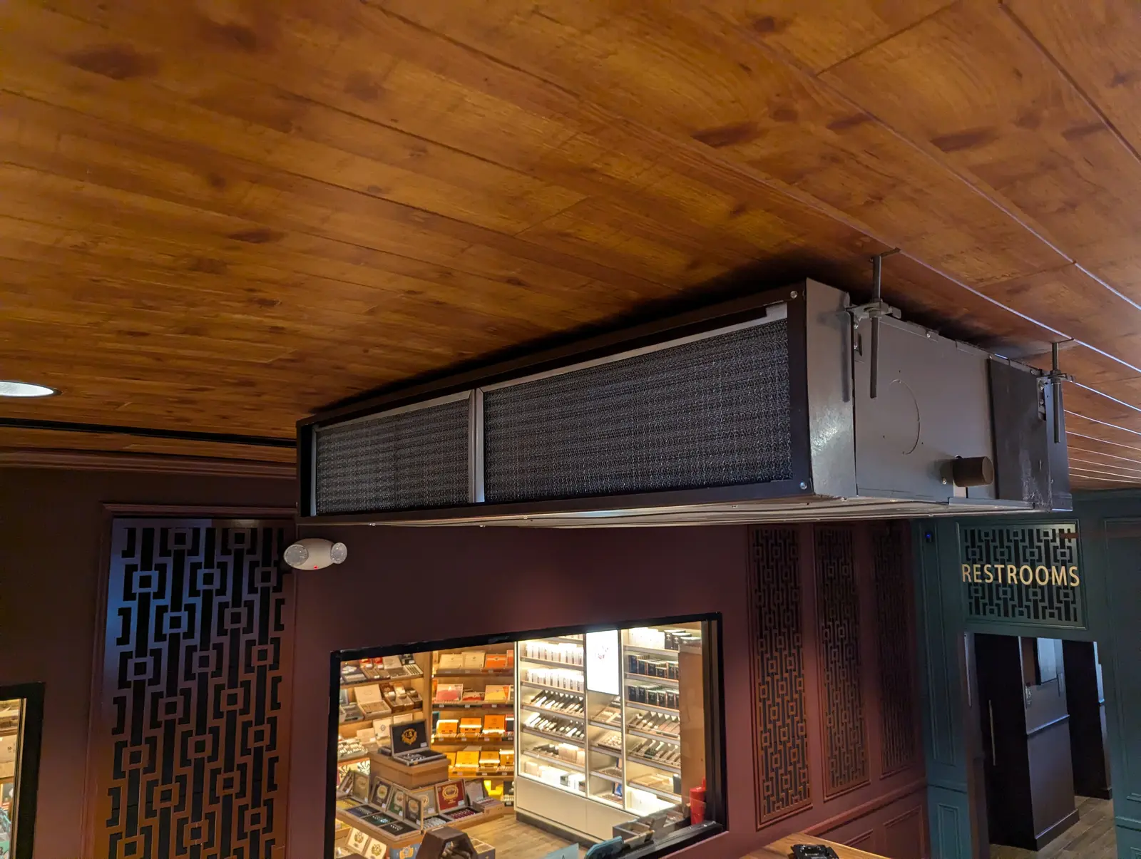 Ceiling-suspended ducted unit under a wood plank ceiling in a commercial lounge