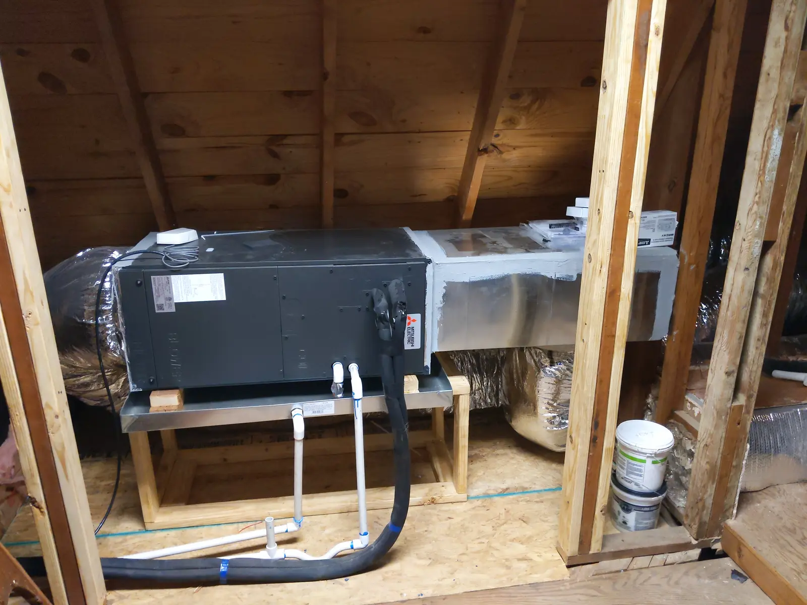 Ducted mini split air handler on a platform inside a framed attic space