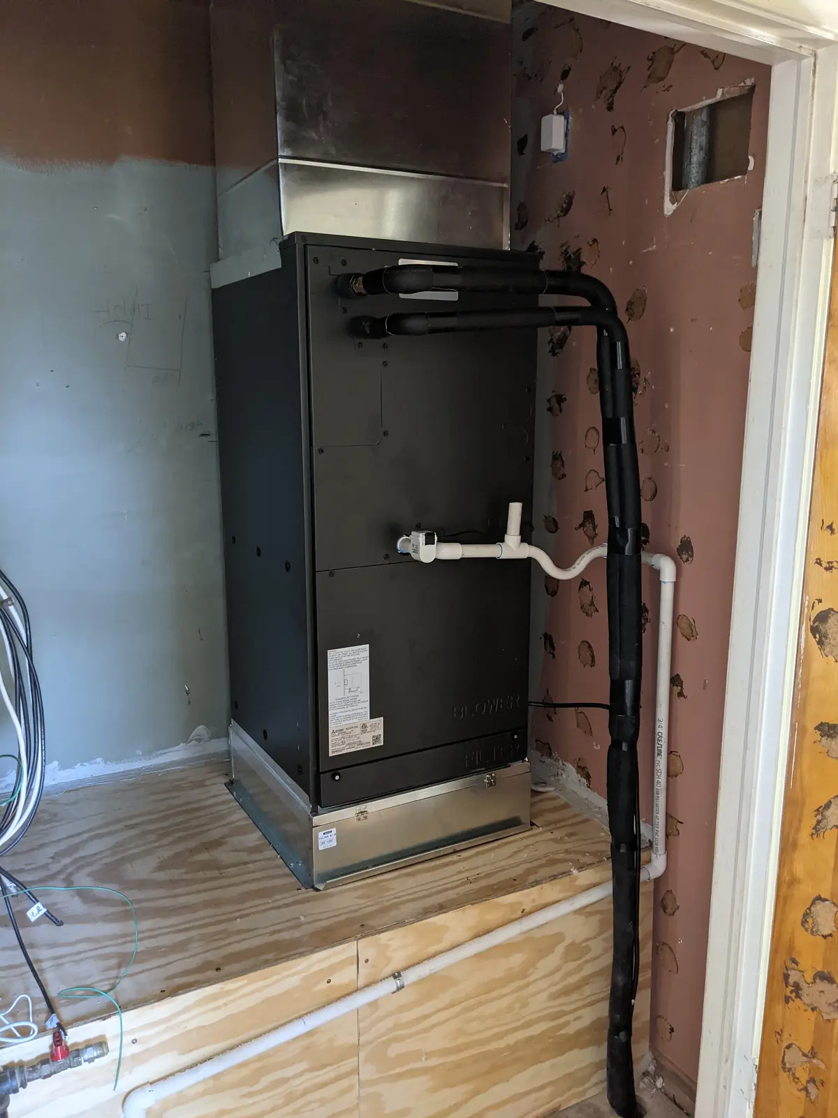 Vertical ducted mini split air handler installed in a closet with refrigerant lines