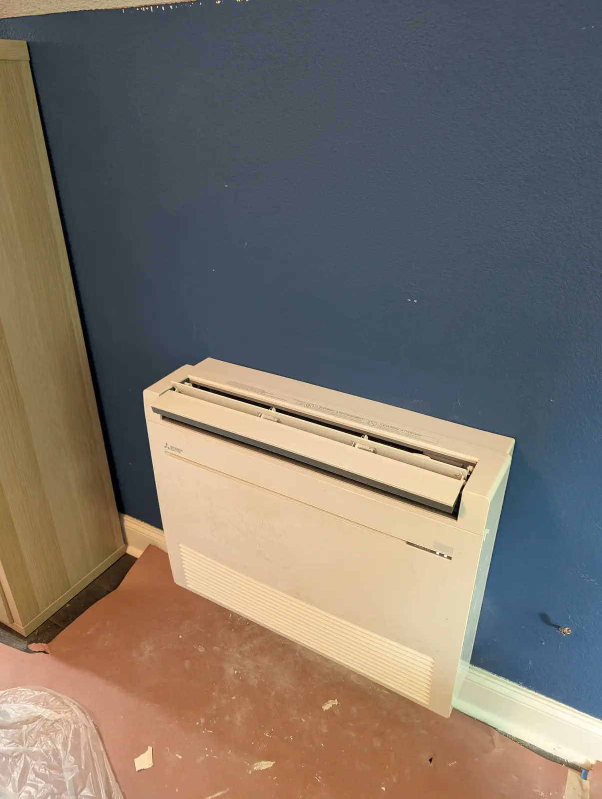 Floor-mounted mini split against a navy blue wall