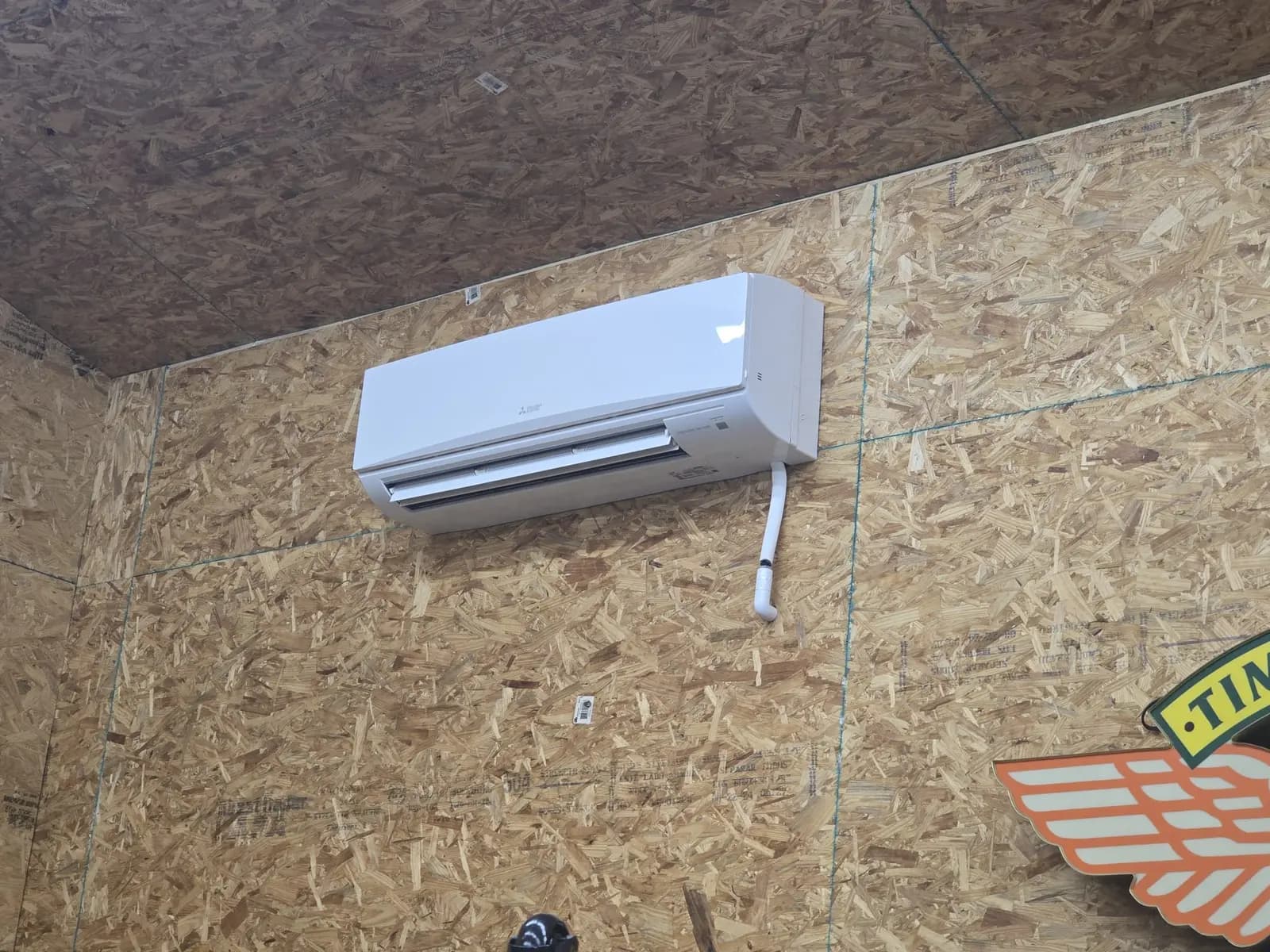 Wall-mount mini split on an OSB wall in a garage workshop