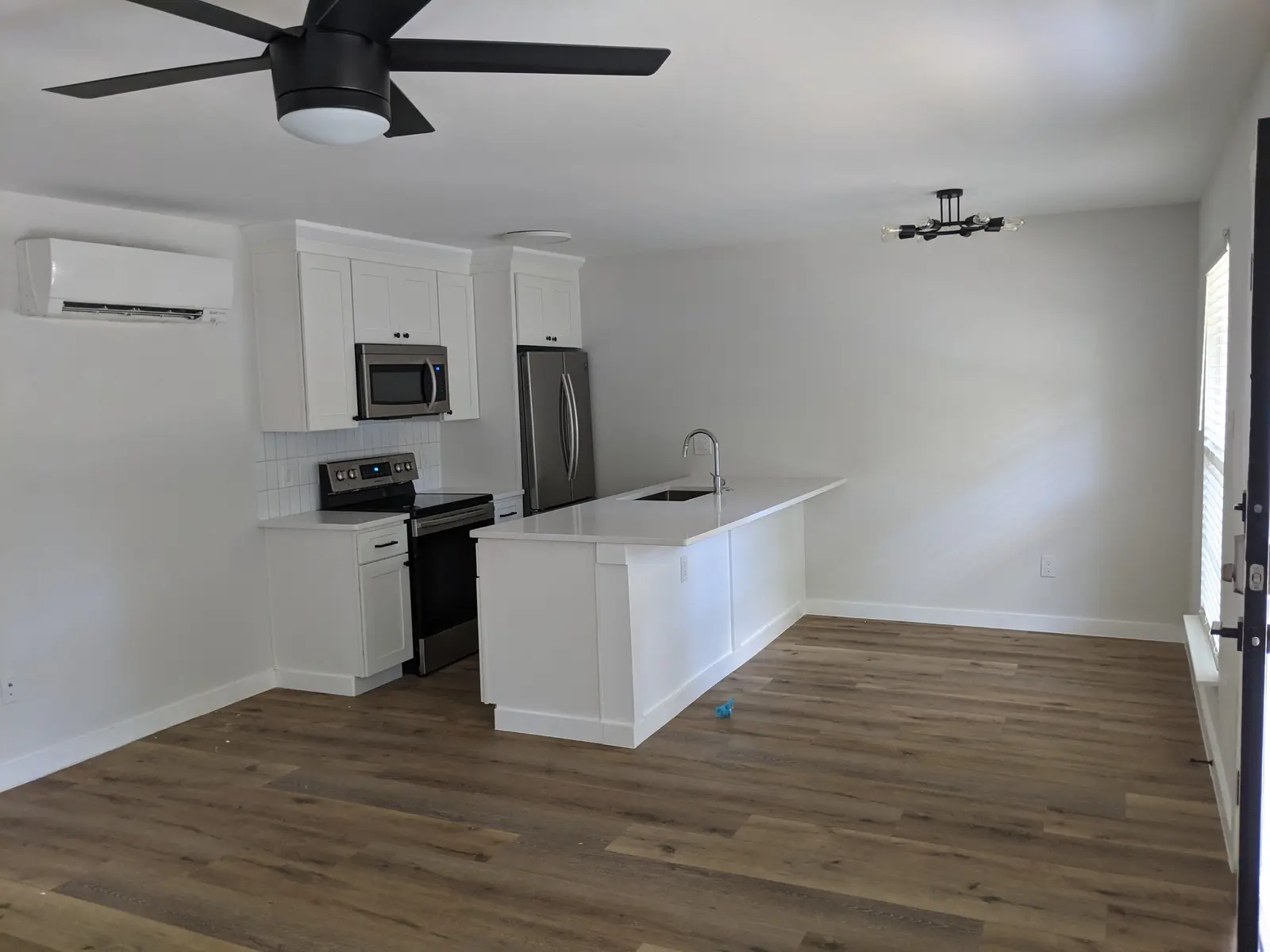 Open kitchen and living area with a wall-mounted mini split above the cabinets
