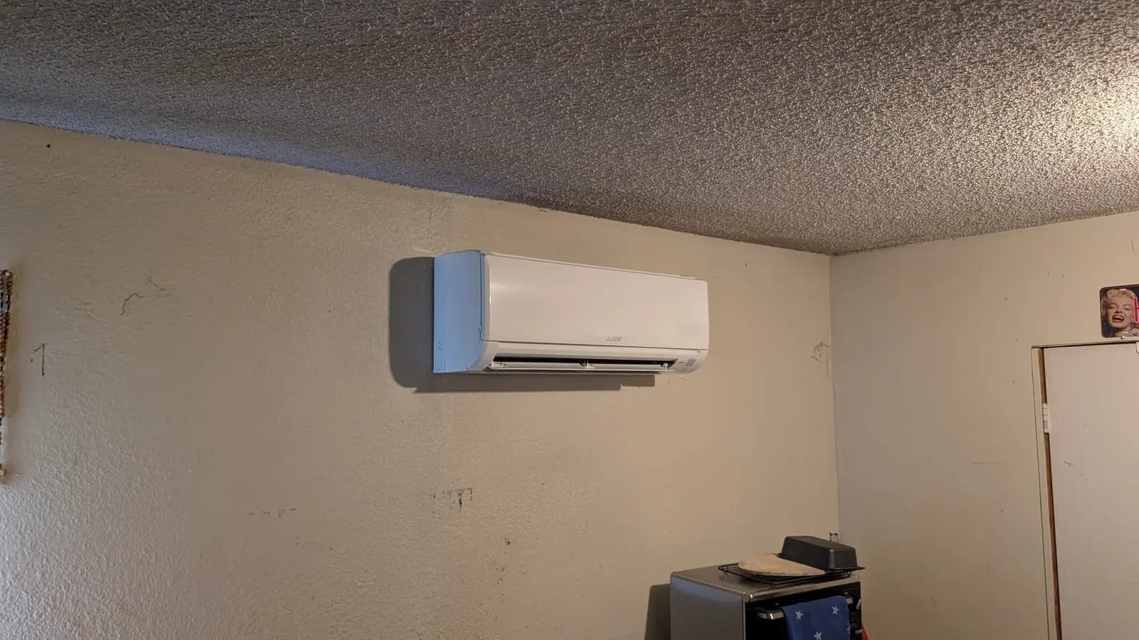 Wall-mount mini split in a room with a textured ceiling