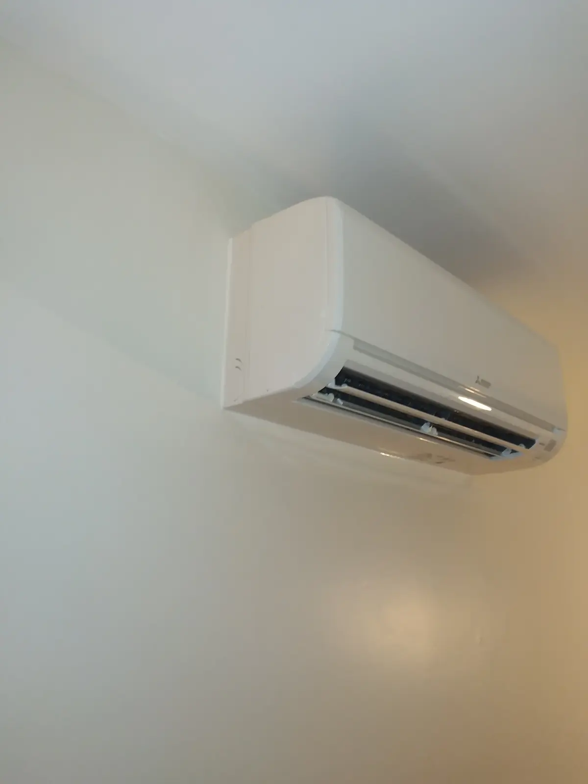 Close-up of a white wall-mounted mini split head on a smooth interior wall