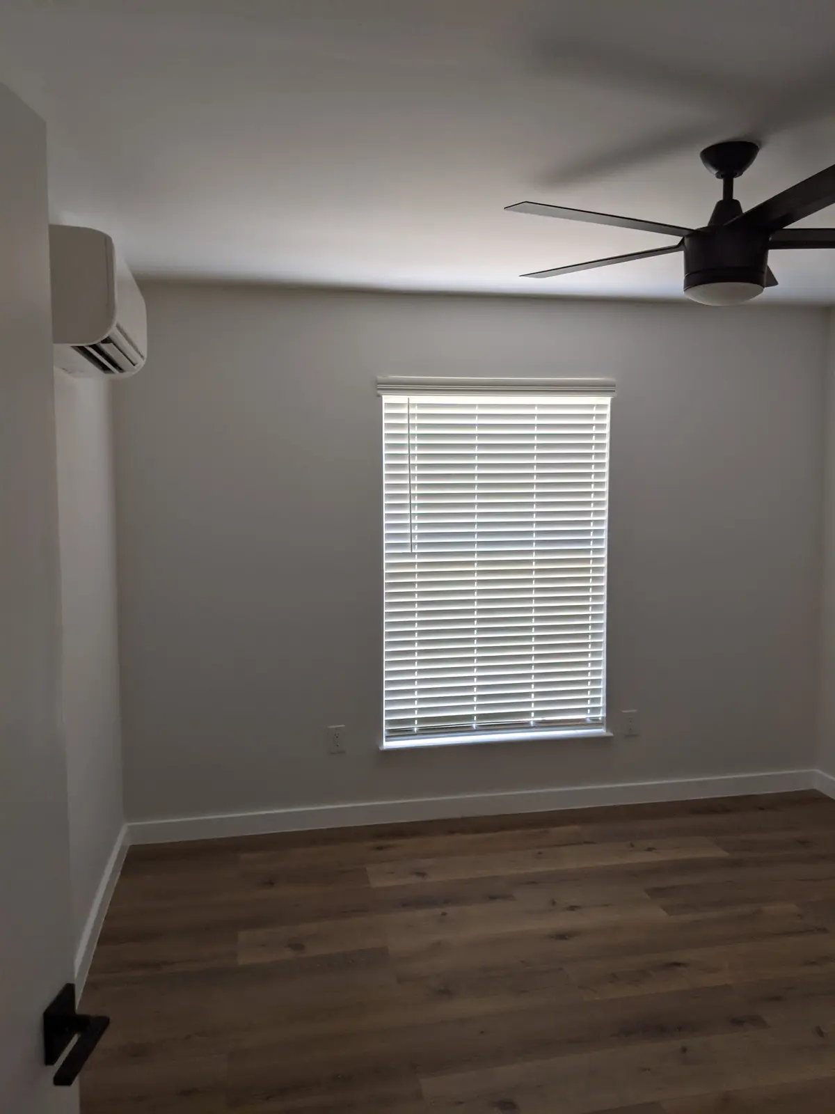 Empty room with a wall-mounted mini split, ceiling fan and window with blinds