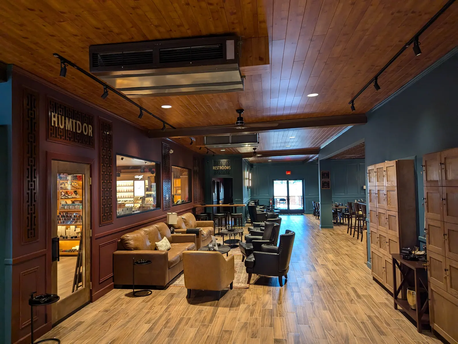 Wide view of a commercial lounge with a ceiling-suspended ducted unit, wood ceiling and leather seating