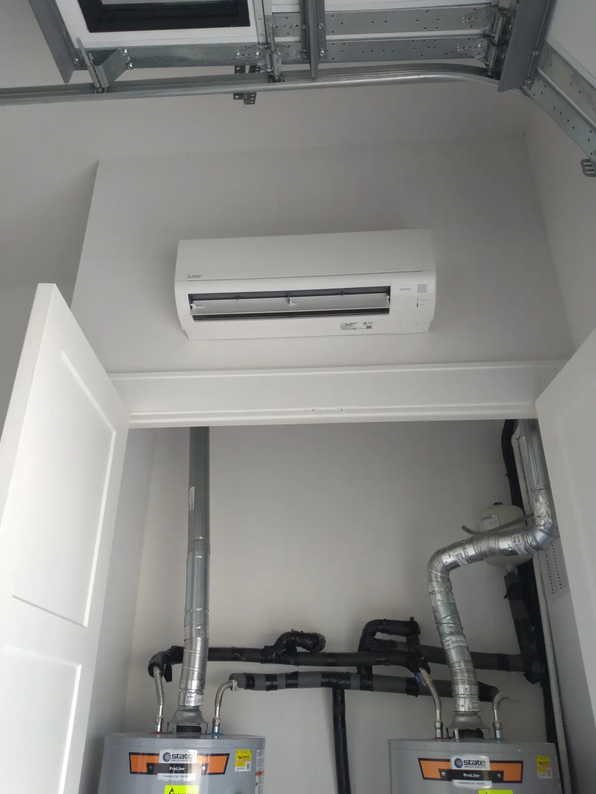 Wall-mount mini split above a water heater closet in a garage