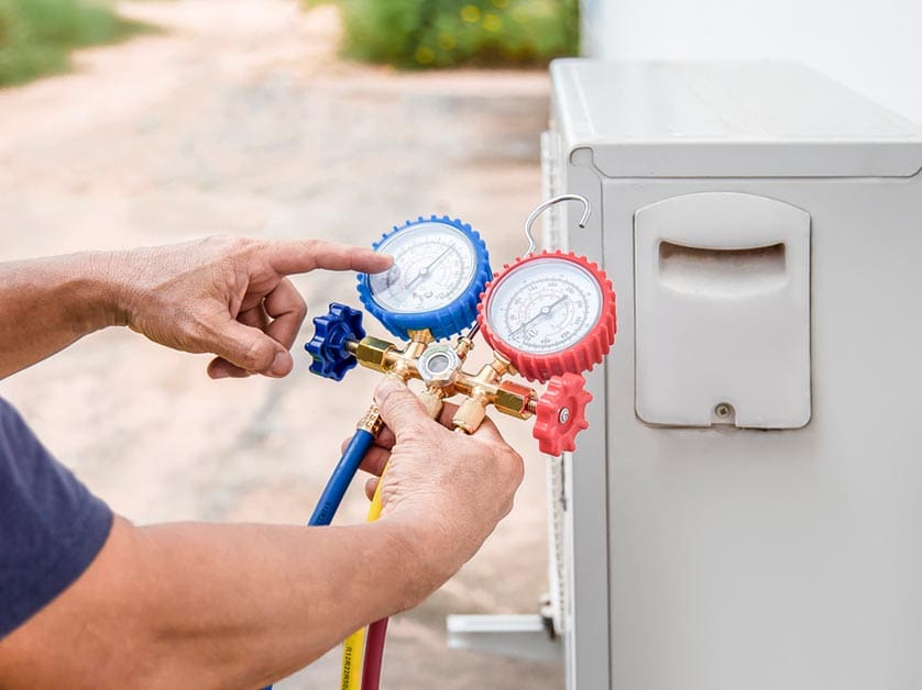 Close-up view of a technician adjusting gauges on a heat pump, showcasing the process of measuring and maintaining system pressure for efficient operation.