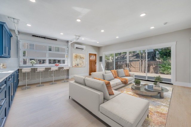 Open concept garage conversion showing living room and kitchen with glass garage door and sliding doors.