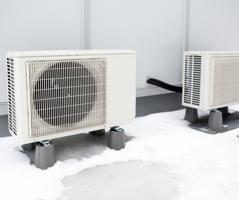 Two white outdoor heat pump condensing units.
