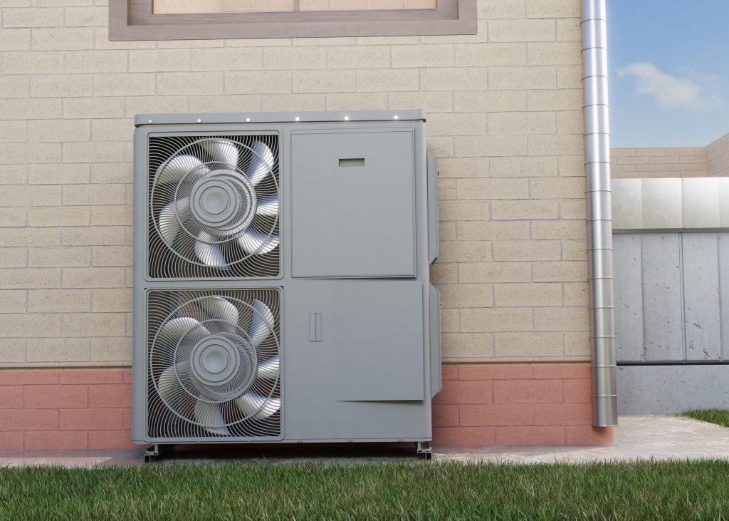 Large outdoor air conditioning unit with two fans mounted against a beige brick wall